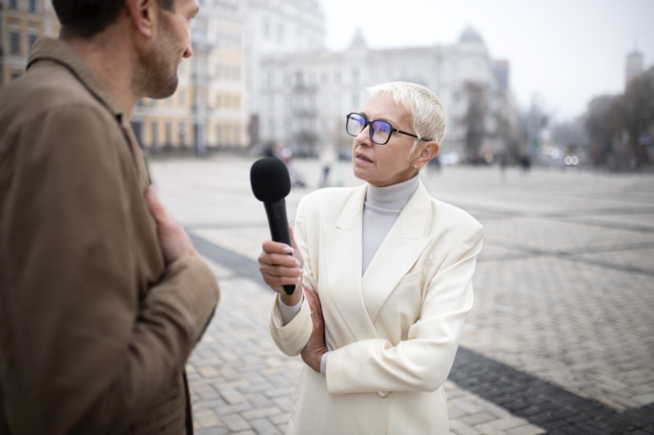 Interview filmen mit einer Kamera – Person hält Mikrofon bei einem Gespräch im Freien
