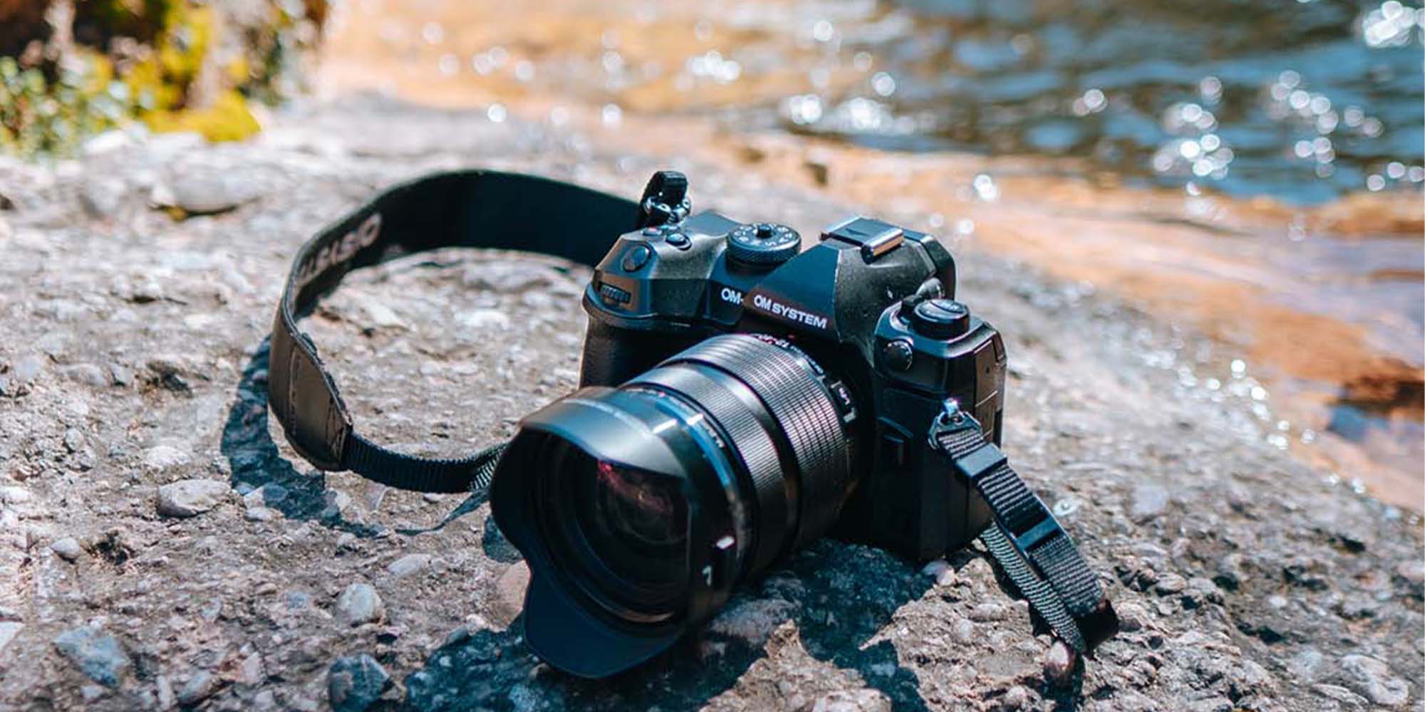 Seitliche Ansicht eines Fotografen mit OM System Systemkamera beim Fotografieren im Wald mit Tageslicht