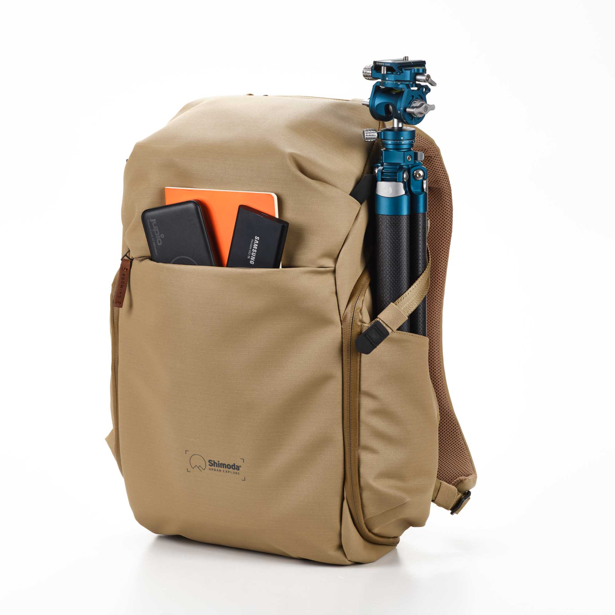 Shimoda Designs Explore 25 Rucksack in Beige, Frontal rechts mit Inhalt in Fronttasche und Stativ in Seitentasche