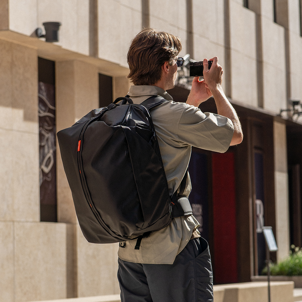 PGYTECH OneMo Travel Backpack 35L in Schwarz beim Tragen im urbanen Einsatz mit Kameraausrüstung.