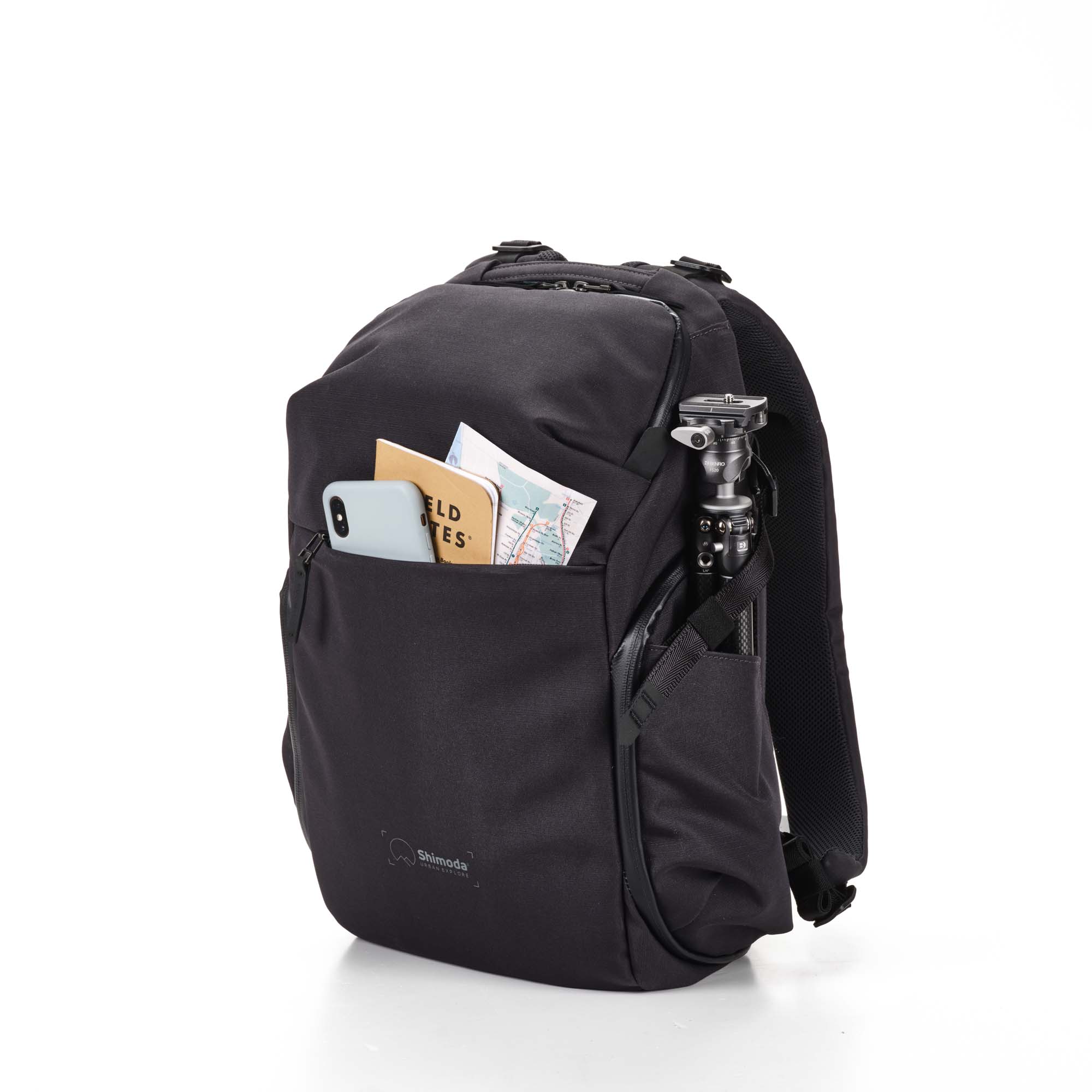 Shimoda Designs Explore 20 Rucksack in Anthrazit, von vorne mit Smartphone, Field Notes und Karte in Fronttasche und Stativ in der Seitentatsche