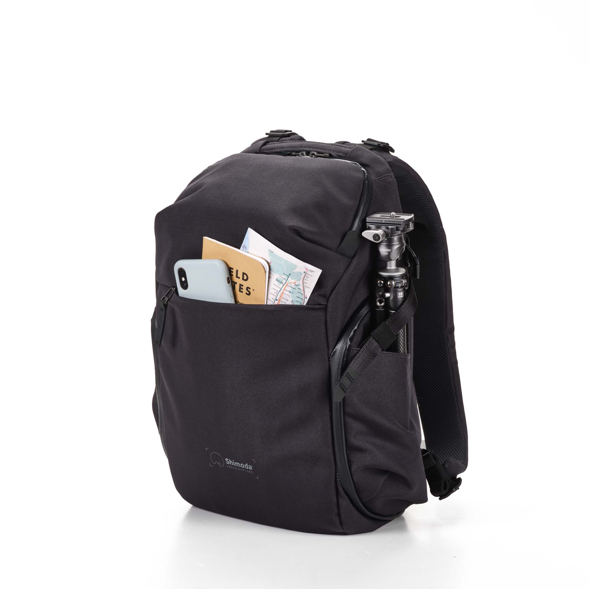 Urban Explore 20 (anthrazit) Shimoda Designs Explore 20 Rucksack in Anthrazit, von vorne mit Smartphone, Field Notes und Karte in Fronttasche und Stativ in der Seitentatsche