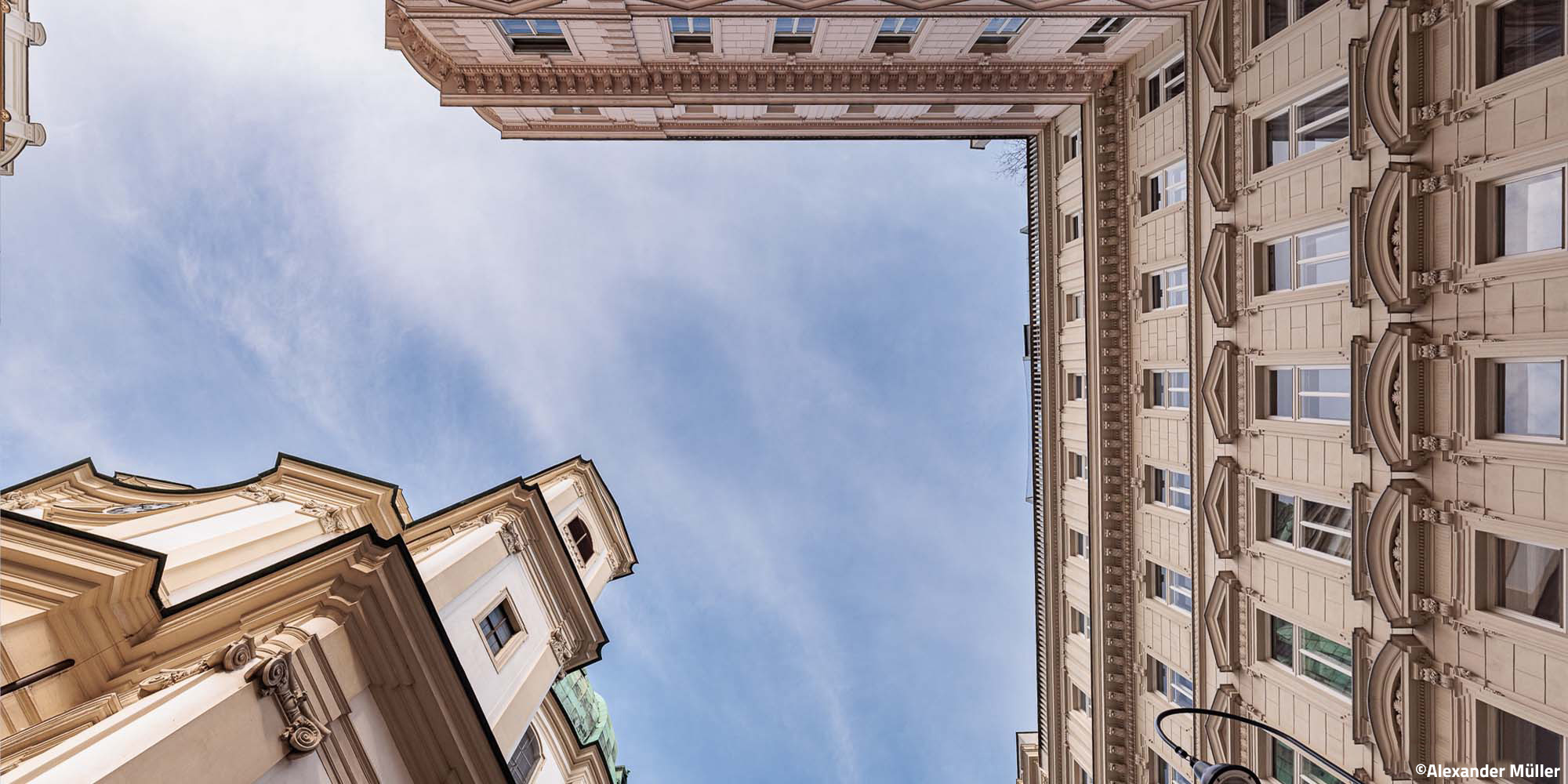 Canon RF 14mm F1.4 – Schräge Perspektive zwischen Gebäuden mit Blick nach oben in klaren Himmel