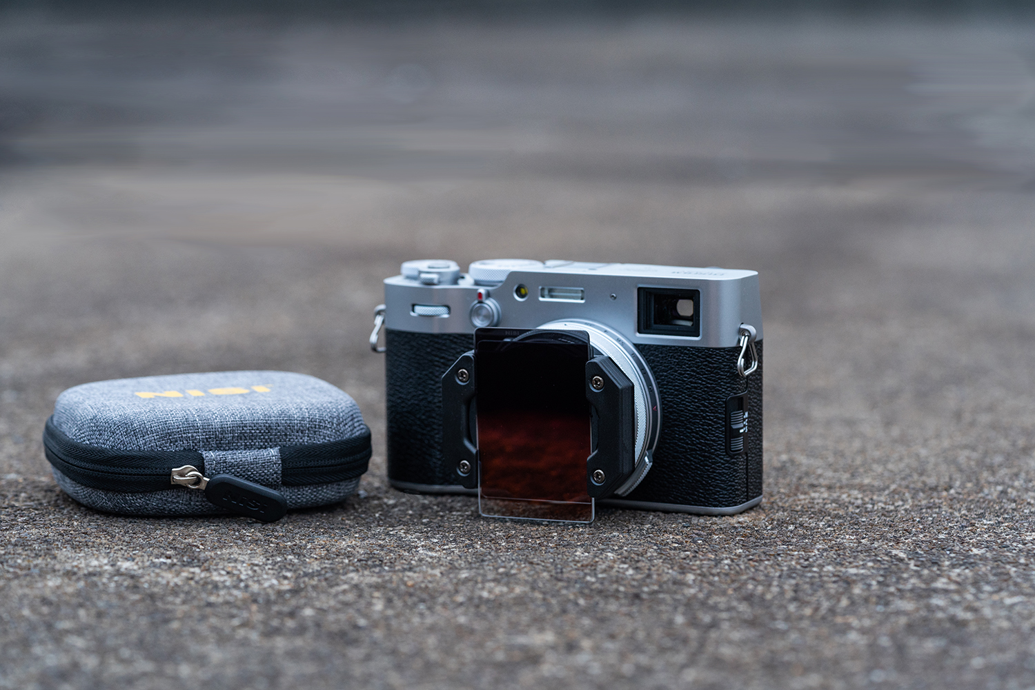 NiSi Filterhalter mit NiSi GND Filter auf Fujifilm X100 Kompaktkamera in Silber, daneben NiSi Kompaktfilter Caddy Lifestyle Bild