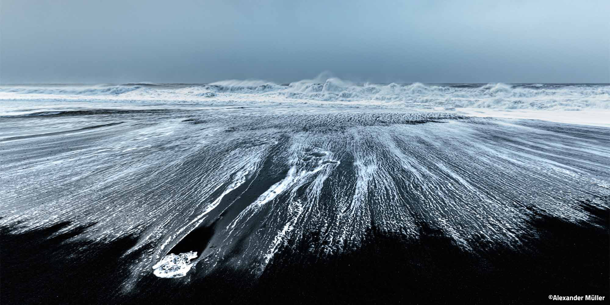 Canon RF 14mm F1.4 – Vorderansicht von Brandung auf schwarzem Sandstrand mit dynamischen Wasserlinien und Gischt