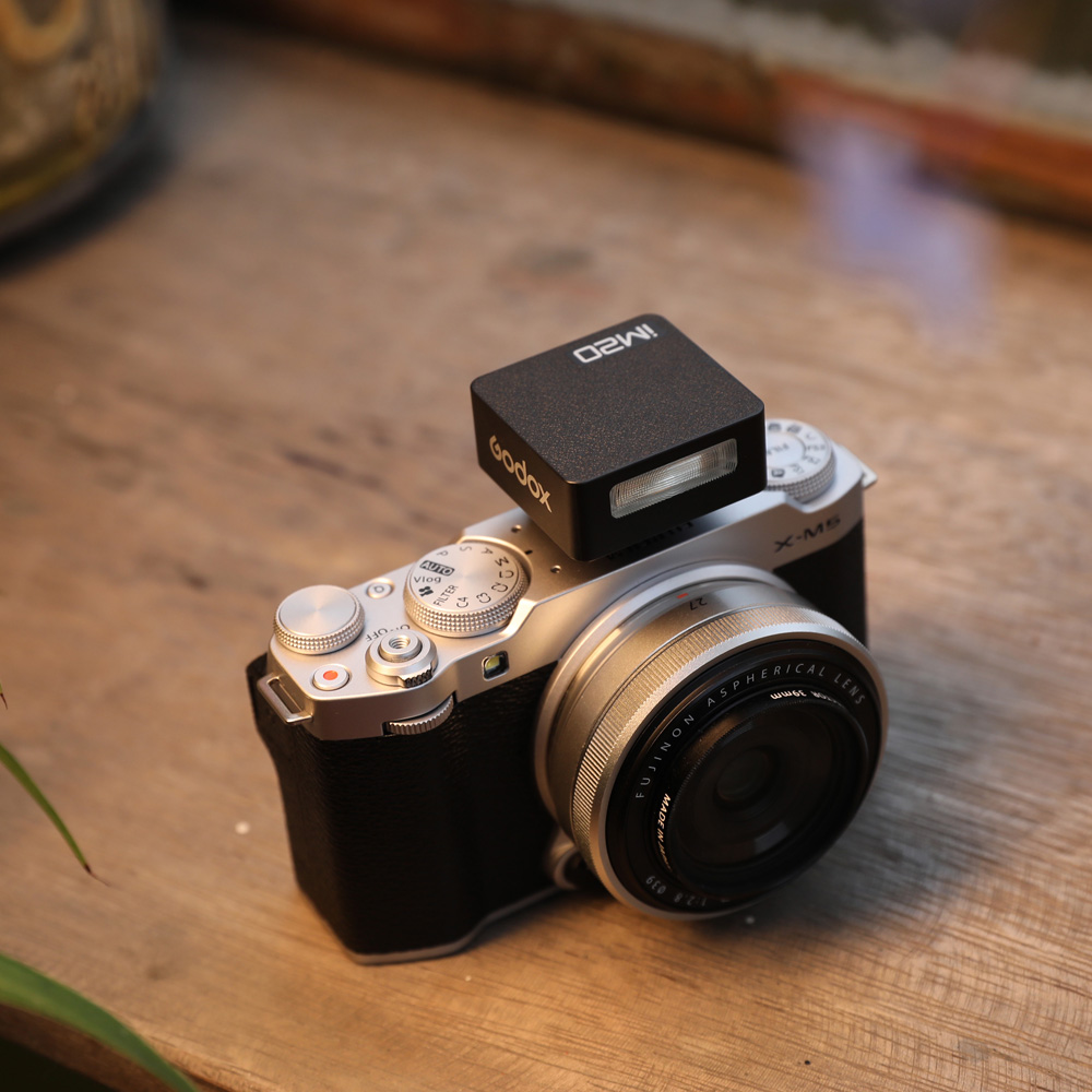 Godox iM20 Blitz – schräge Ansicht montiert auf spiegelloser Kamera, zeigt Einsatz im praktischen Betrieb