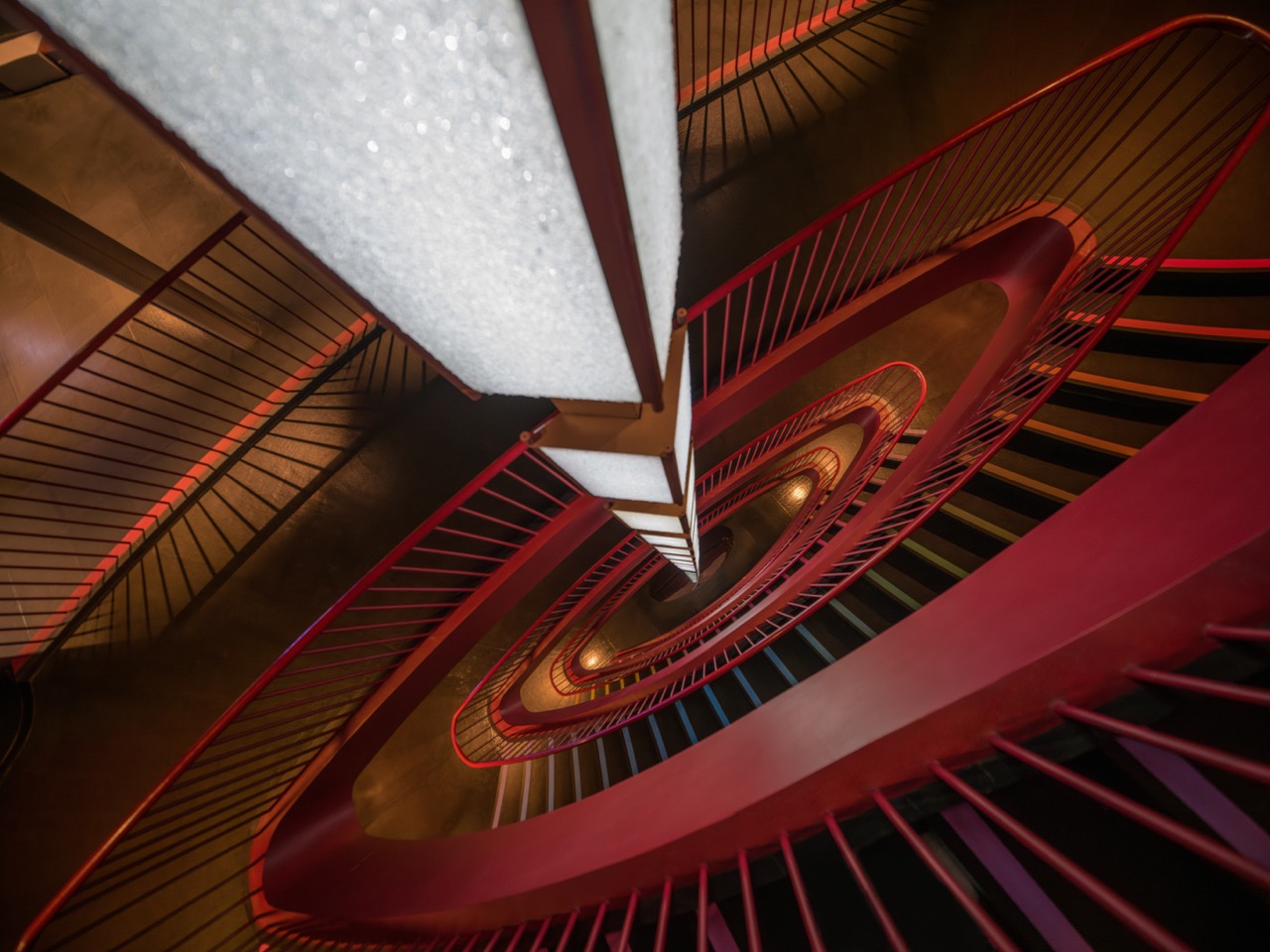 Spiral-Treppenhaus in Draufsicht mit roten Geländern und geometrischer Linienführung im Innenraum