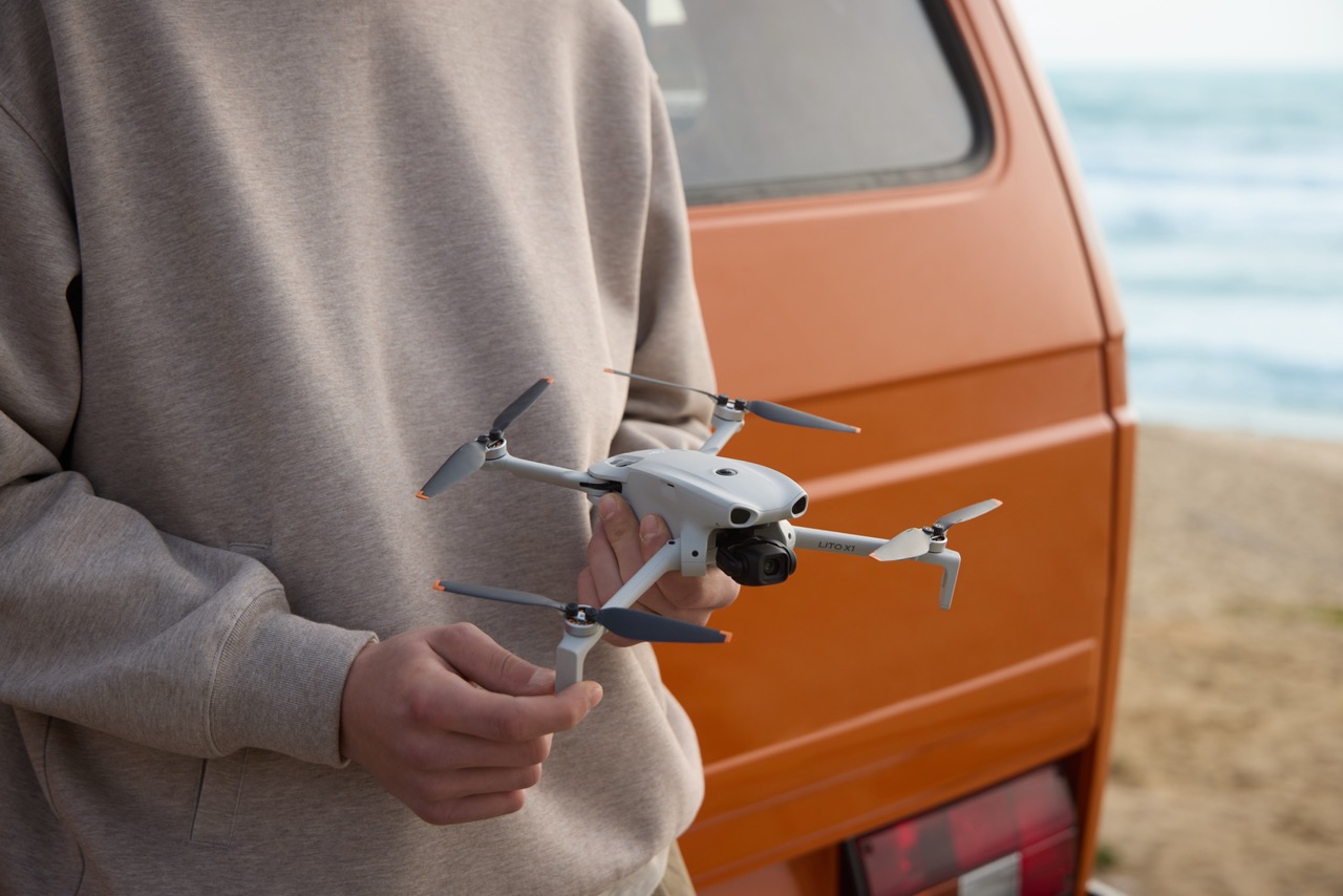 DJI Lito Serie Drohne – Detailansicht in der Hand mit ausgeklappten Rotorarmen vor Van am Strand
