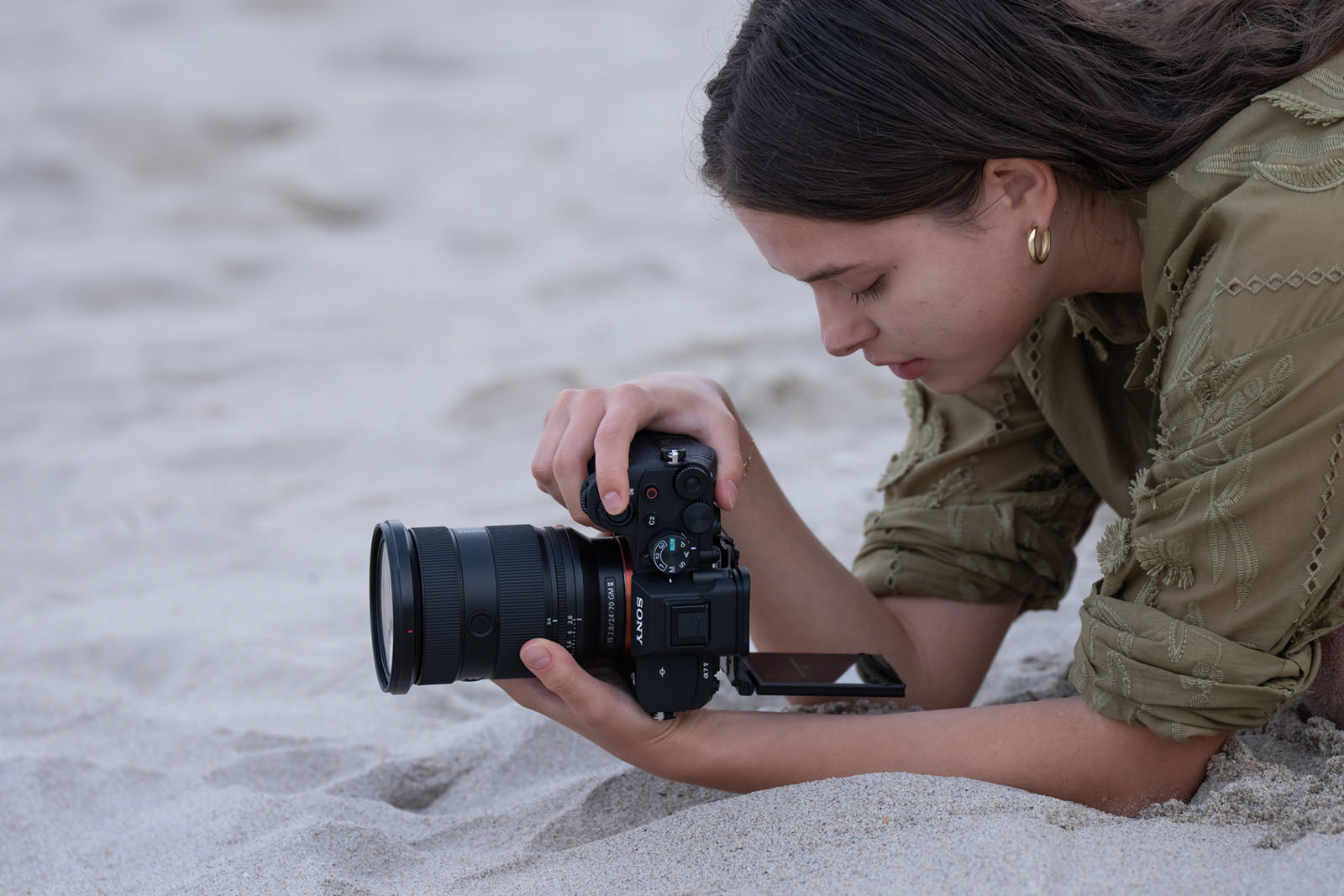 Sony Alpha 7 V im Einsatz am Strand, Fotografin nutzt Kamera mit Objektiv und ausgeklapptem Display