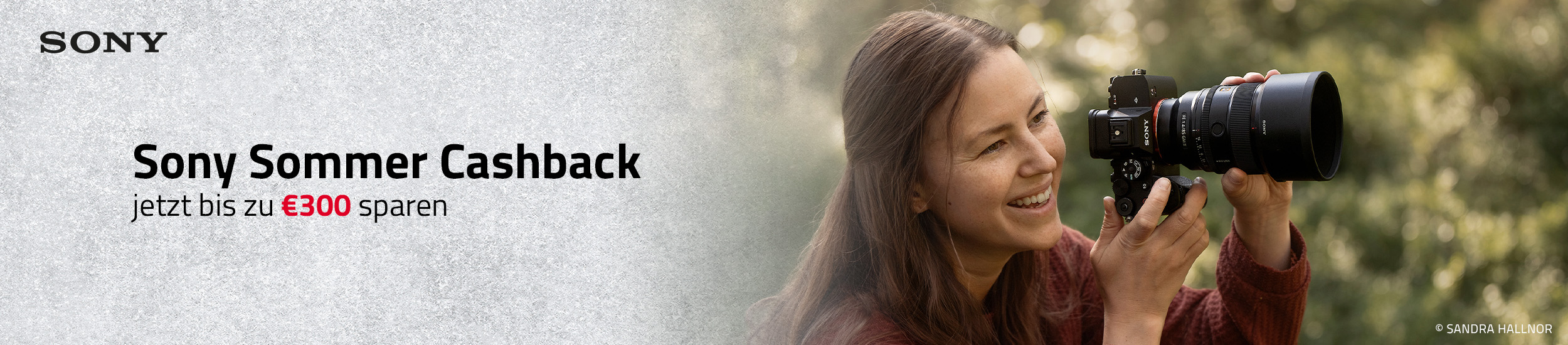 Sony Systemkamera mit Teleobjektiv in Nutzung, Person fotografiert im Freien während Sommer Cashback Aktion