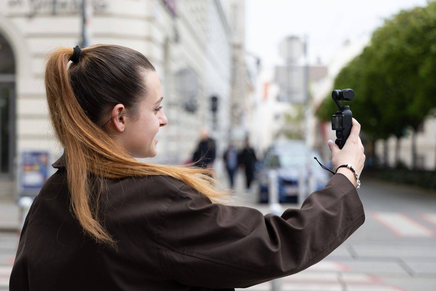 DJI Osmo Pocket 3 bei Vlogging-Anwendung, seitliche Ansicht mit Nutzerin beim Filmen in der Stadt