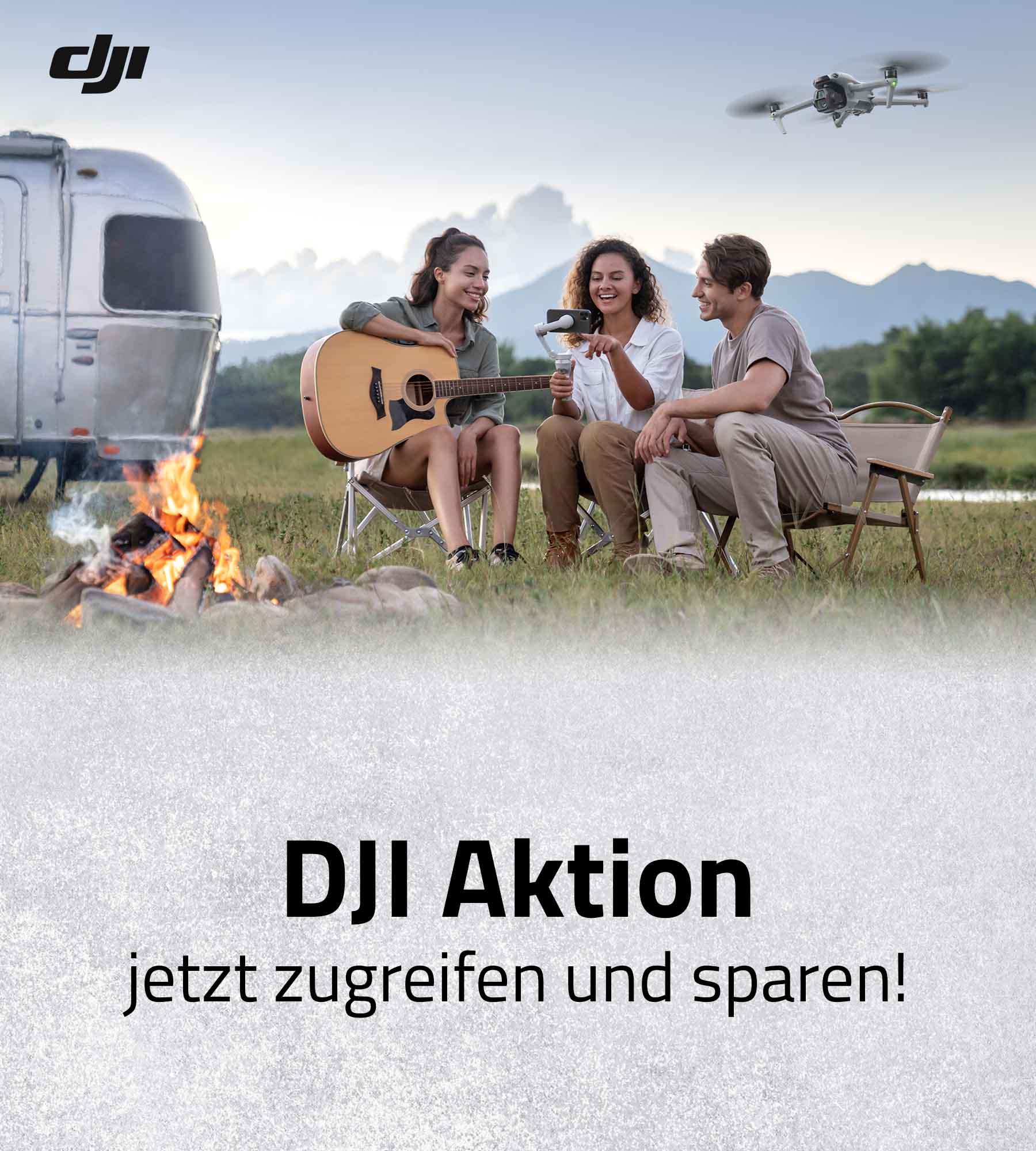 DJI Drohne im Flug über Campingplatz, drei Personen sitzen am Lagerfeuer mit Gitarre vor Wohnwagen