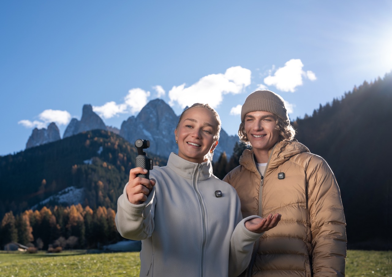 DJI Osmo Pocket 4 – Nutzung im Freien für Selfie-Videoaufnahme vor Berglandschaft mit zwei Personen