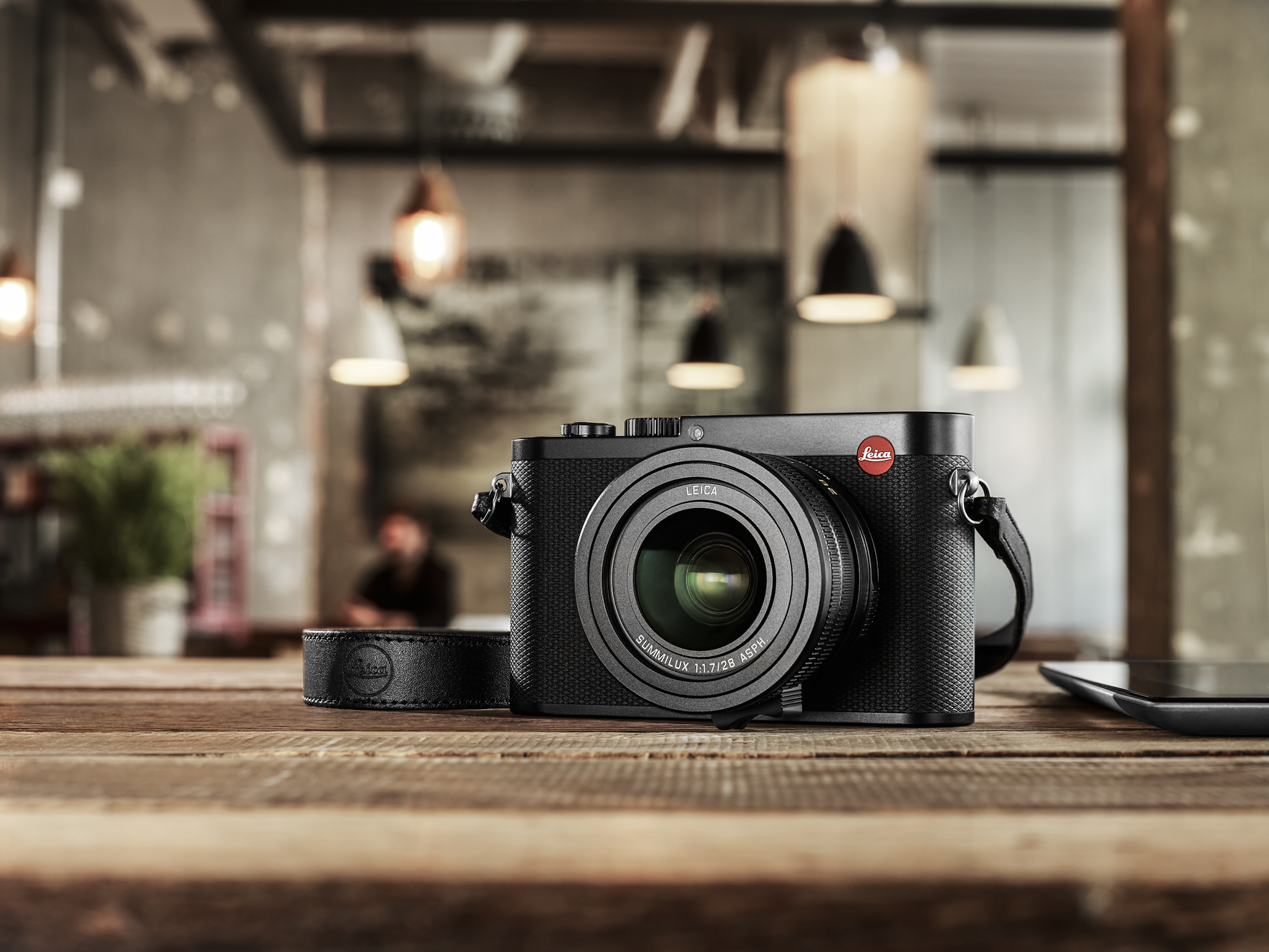 Leica Q Kamera auf Holztisch – Alltagsszene mit Objektiv und unscharfem Hintergrund in Innenraum