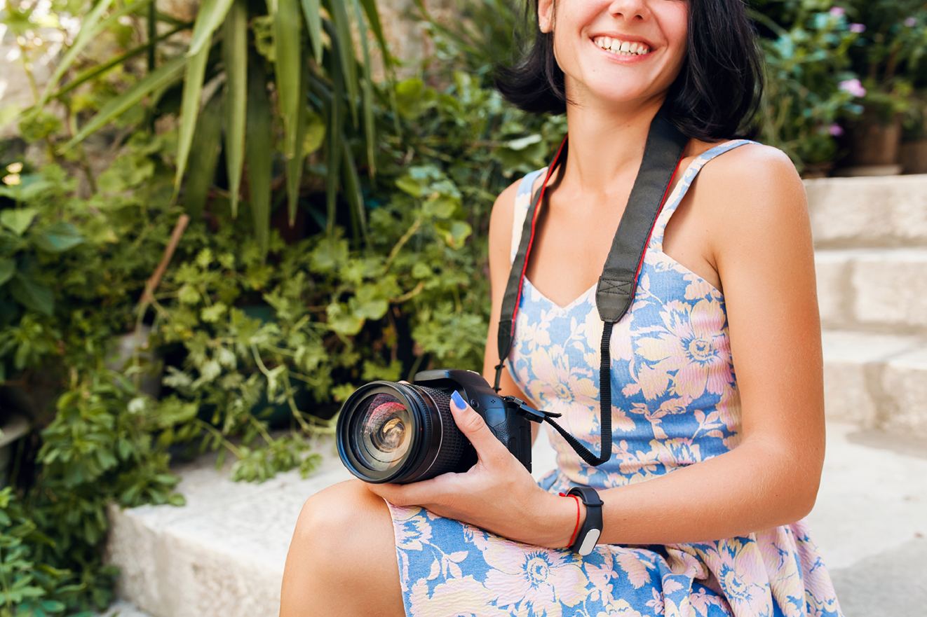 Reisefotografie – Frau mit Kamera auf Steintreppe in einem grünen Garten