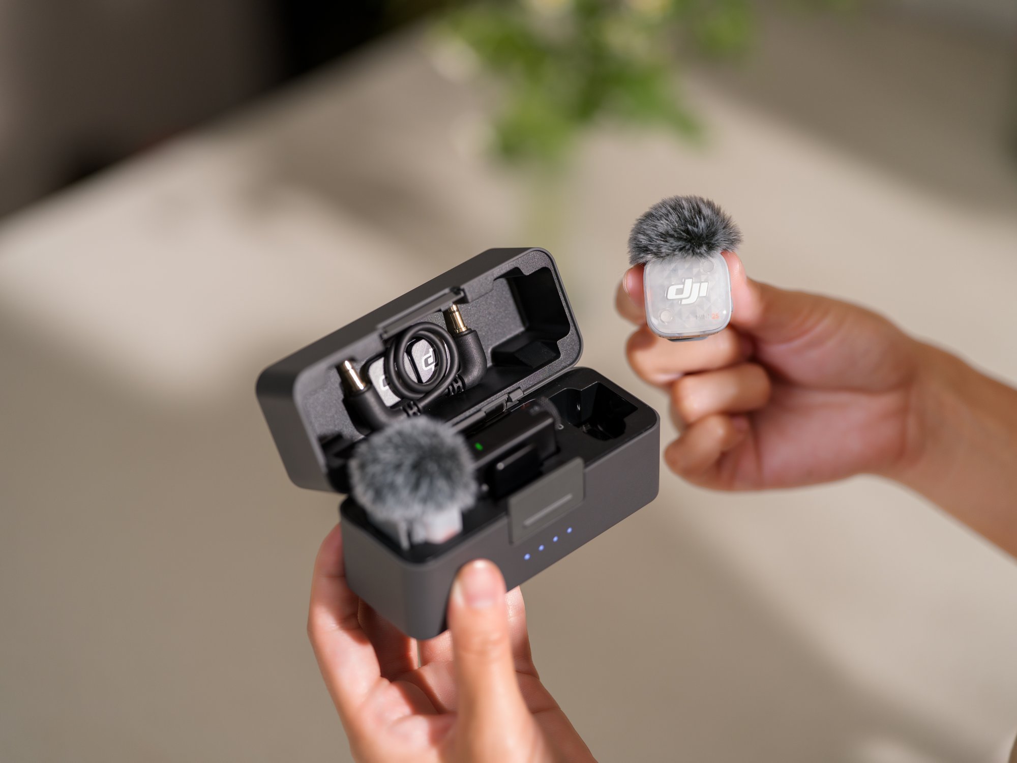 DJI Mic Mini 2S im Einsatz mit geöffneter Ladeschale und entnommenem Sender mit Windschutz.