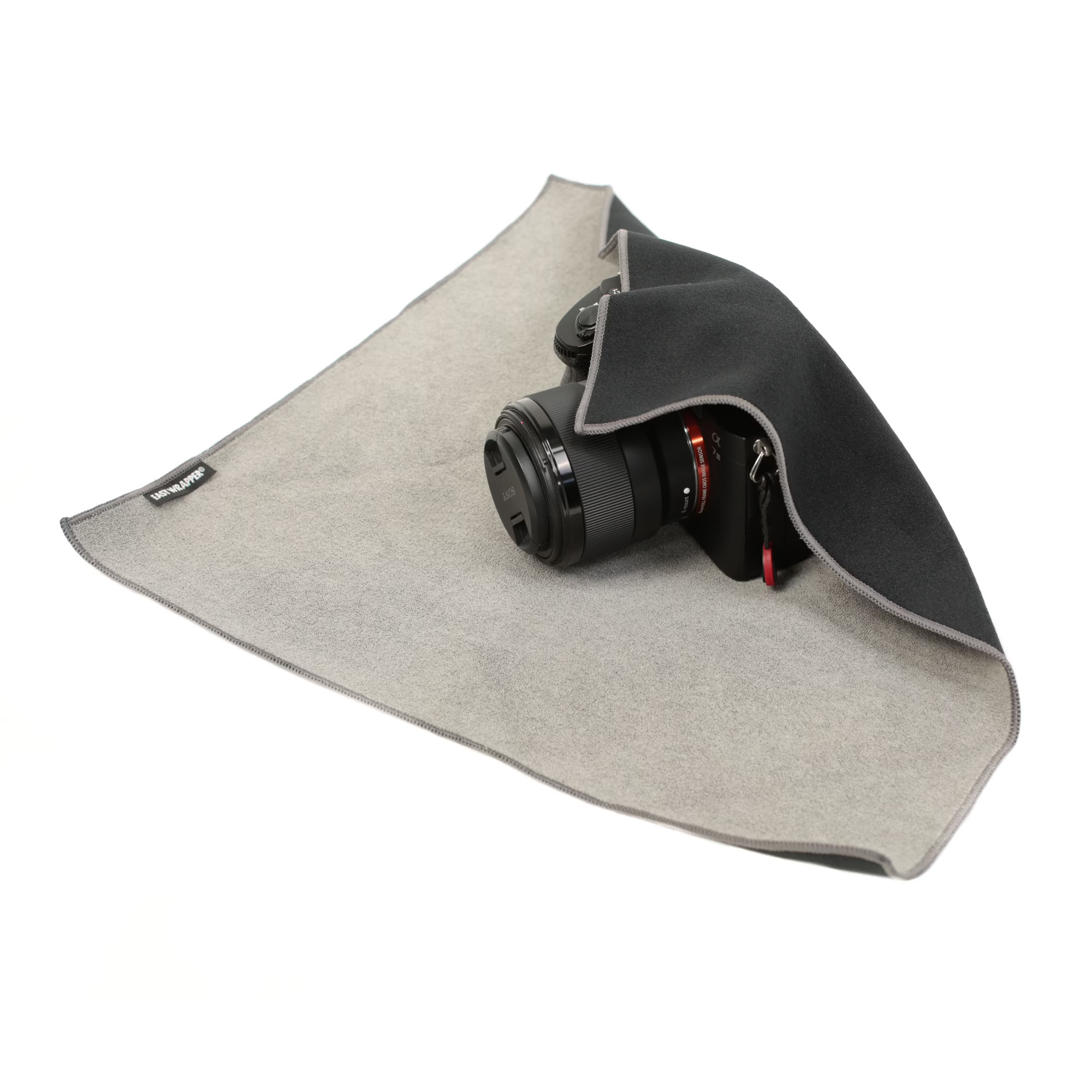 Selbsthaftendes Einschlagtuch M in Schwarz, angewendet um eine Kamera mit Objektiv zum Schutz beim Transport