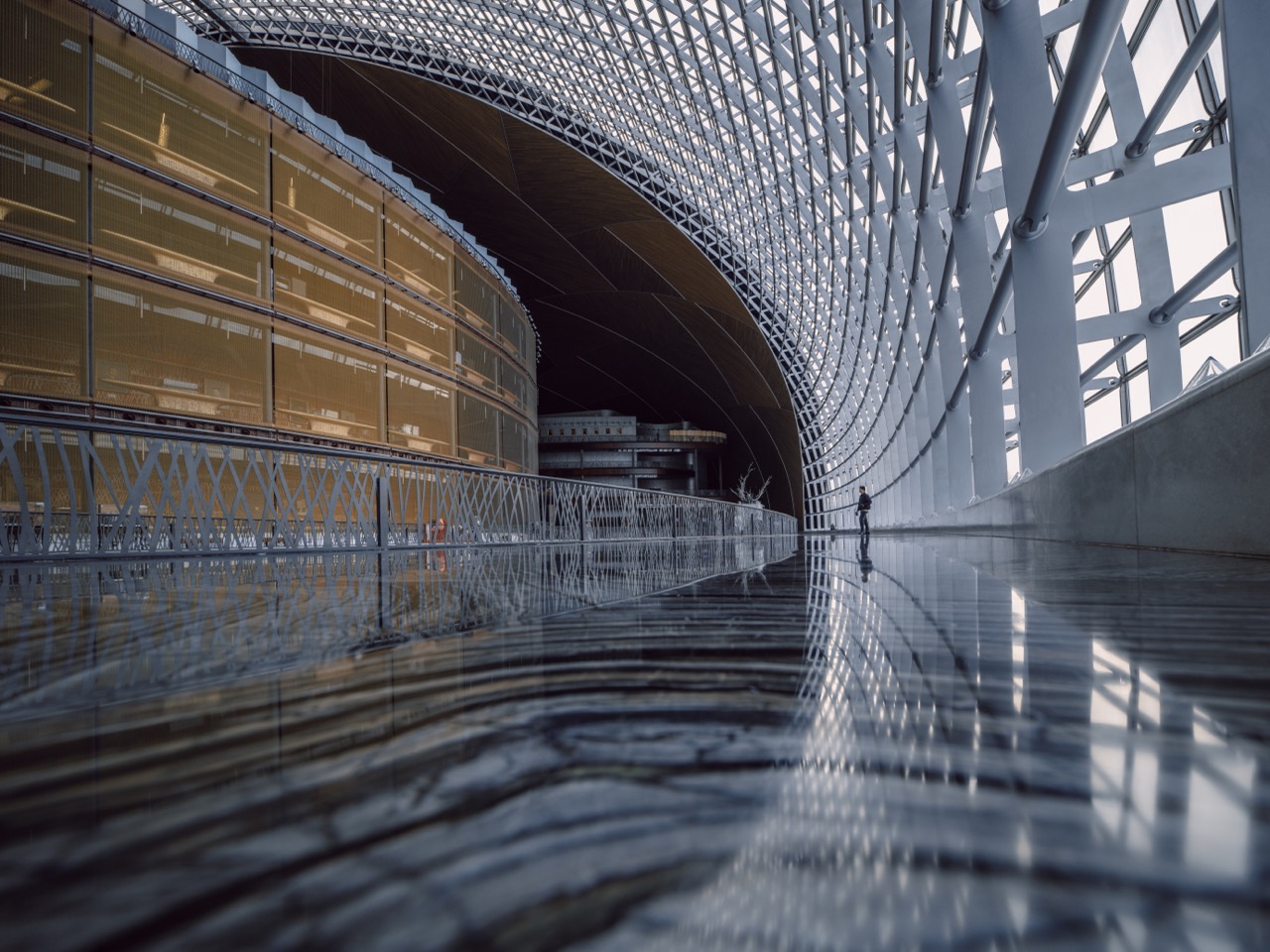 Moderne Halle mit geschwungener Glasstruktur und reflektierendem Boden in weiter Perspektive