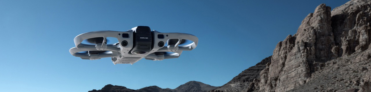 DJI Avata 360 – Schräge Ansicht der kompakten FPV-Drohne im Flug vor klarem Himmel und Felslandschaft